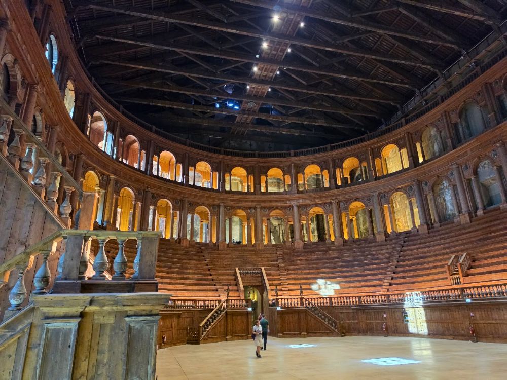 Istorinio Teatro Farnese teatro interjeras Parmoje su puslankiu išdėstytomis medinėmis žiūrovų tribūnomis ir dviem arkadų aukštais. Virš teatro salės kyla aukštos medinės stogo konstrukcijos, o apačioje matomi du lankytojai.